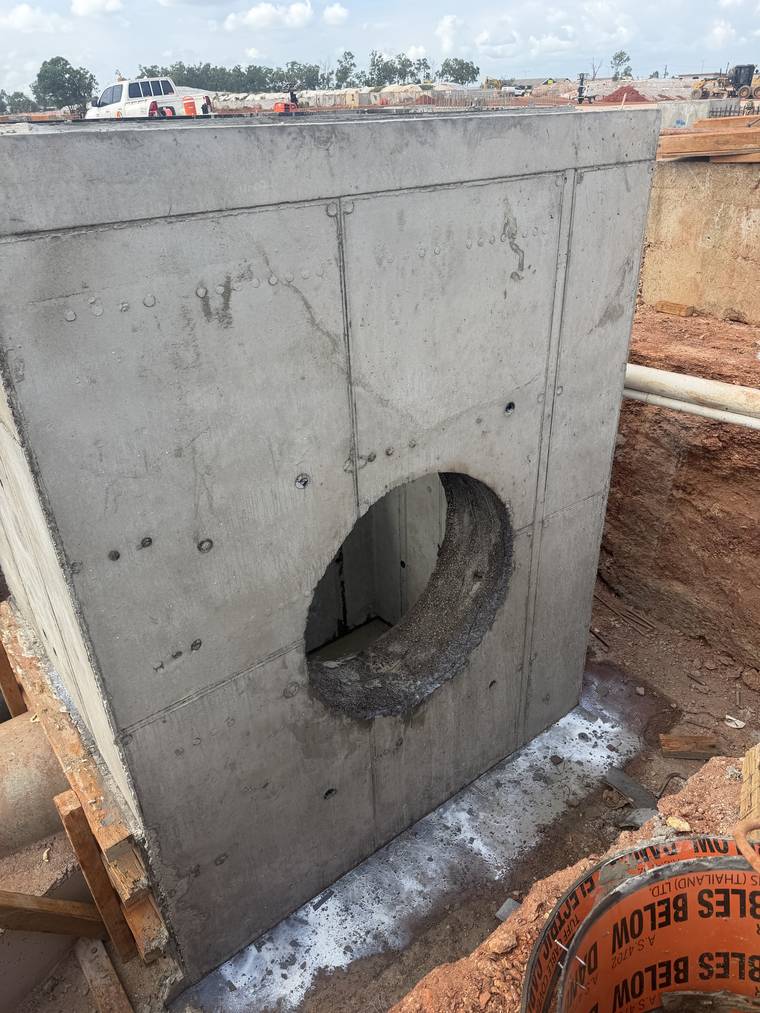 Completed in-situ concrete stormwater pit standing in red earth at sunrise.