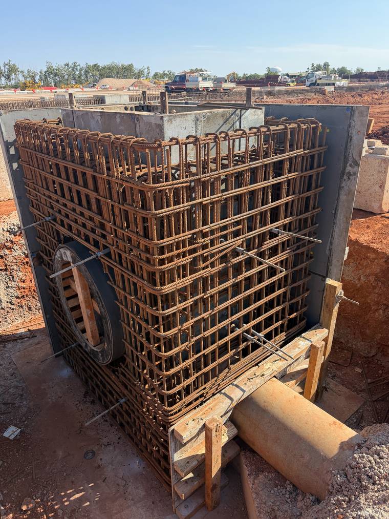 Corner of a pit reinforcement cage with a circular blockout set for the pipe penetration.