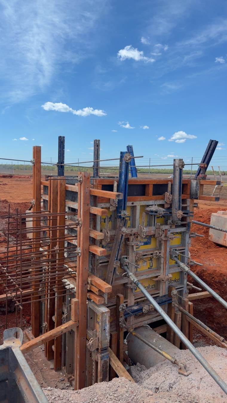 Wall and column formwork erected with push-pull props against a clear blue sky.