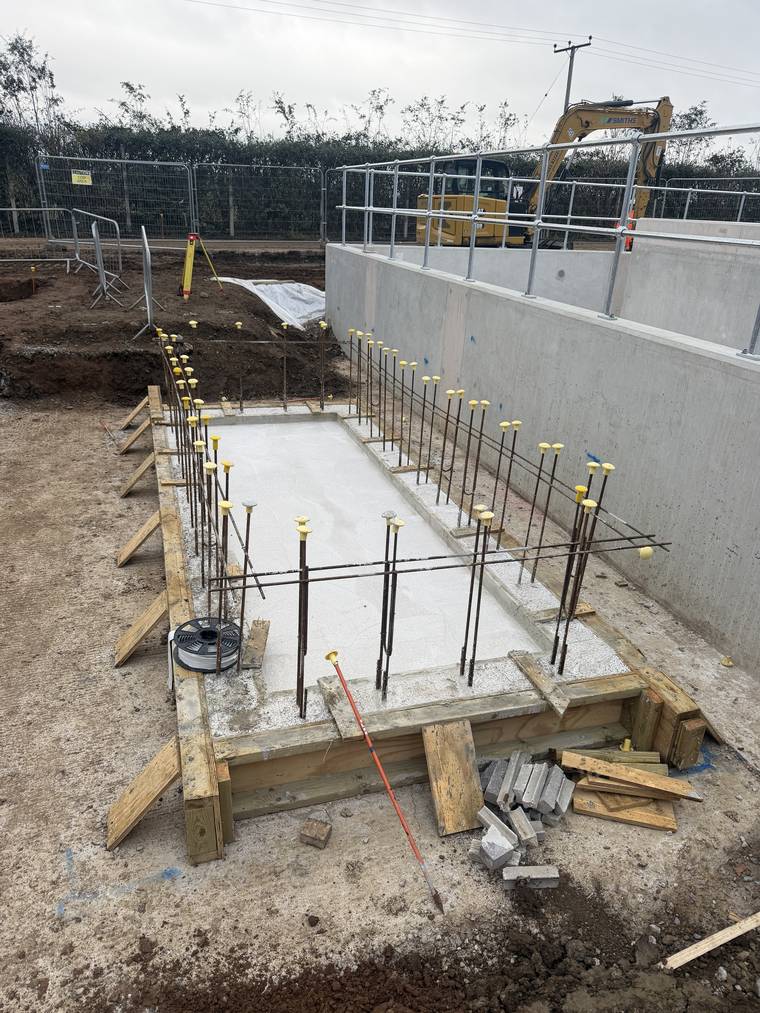 Completed slab and kicker with capped starter bars, next to a poured in-situ concrete wall.